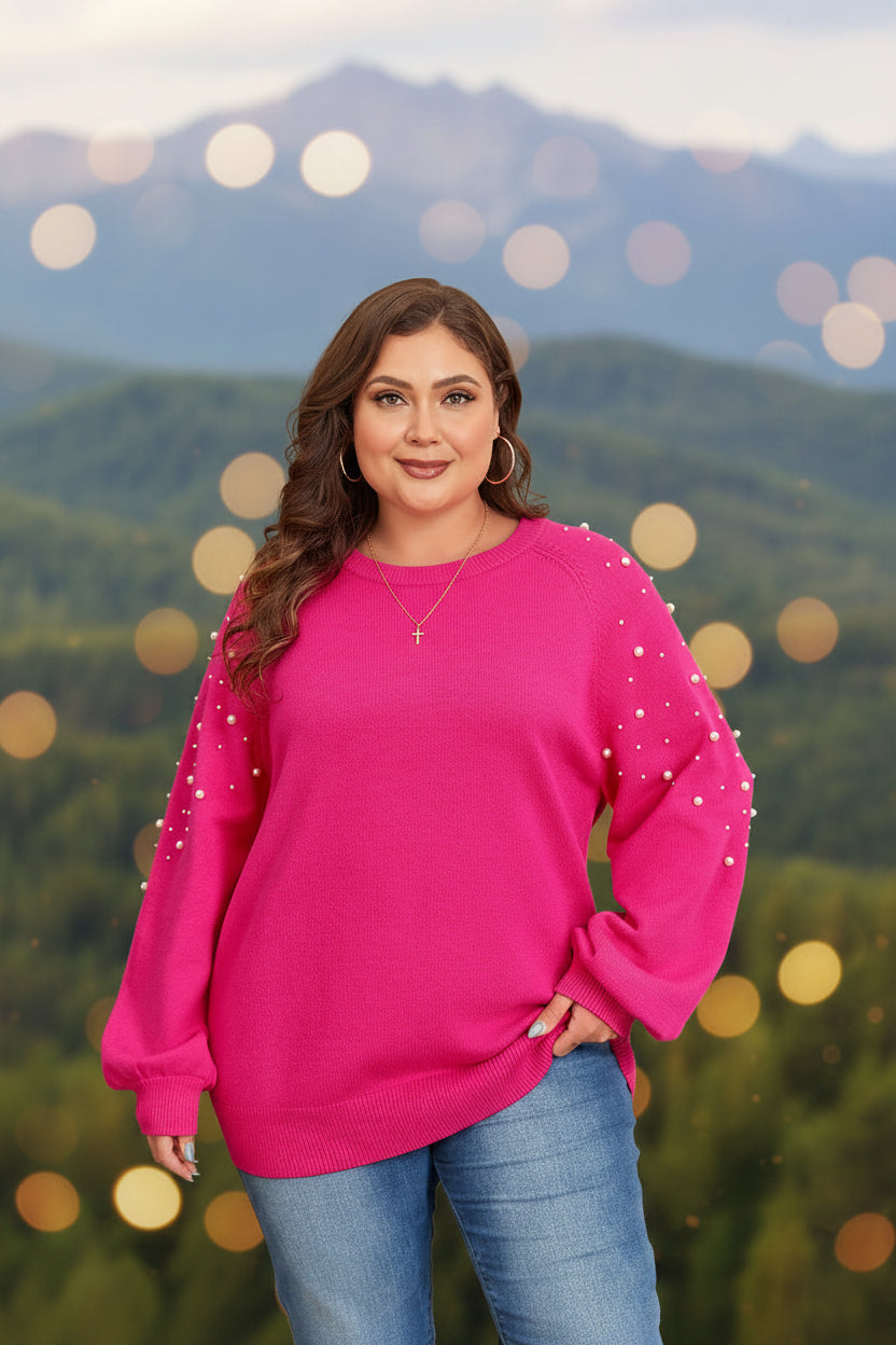 Woman wearing a pink sweater with pearl embellishments in a festive setting.