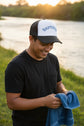 A white and navy blue trucker hat with 'BAPTIZED' embroidered in blue arched letters on the front white panel.