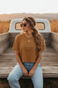 Brown crop top  with text stating, "It's Just Earth, Chill Out, Romans 12:2" on a white background