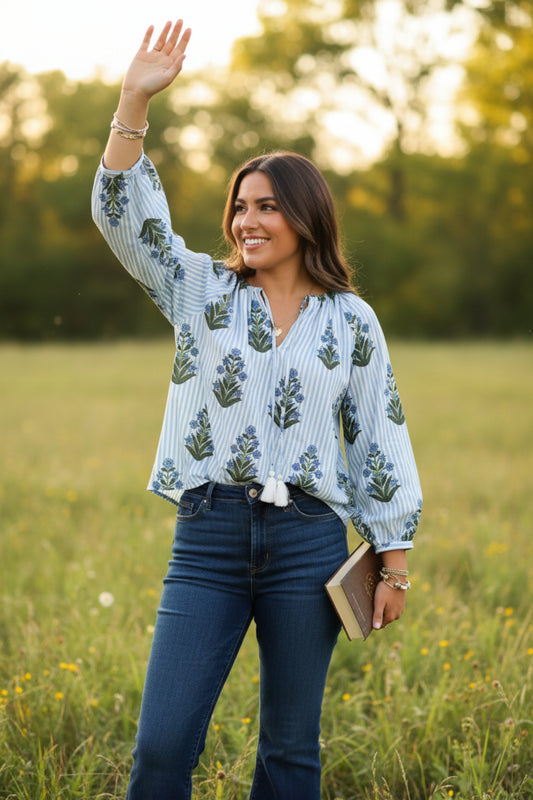 Woman wearing a floral and striped blouse with a blurred background