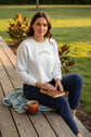 An off-white crewneck sweatshirt featuring the text 'Jesus set me Free' printed in black on the chest and a vertical multicolor floral pattern down the right sleeve, displayed on an outdoor background.