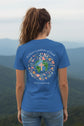 A blue short-sleeve t-shirt shown from the back, featuring a colorful graphic of a globe with a cross, surrounded by flowers in a circular frame, with the text '#Have a pattern of faith' and '#Not conformity' in white script.