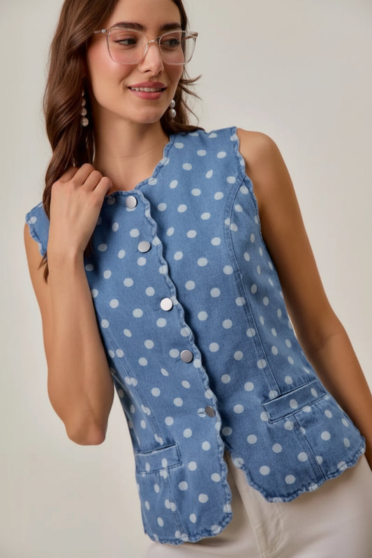 Woman wearing a blue polka dot vest against a plain background