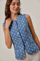 Woman wearing a blue polka dot vest against a plain background
