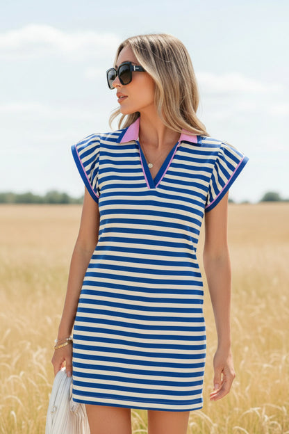 Woman wearing a blue and white striped dress with a pink collar indoors.