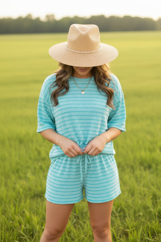 Woman wearing a turquoise striped outfit with a necklace indoors.