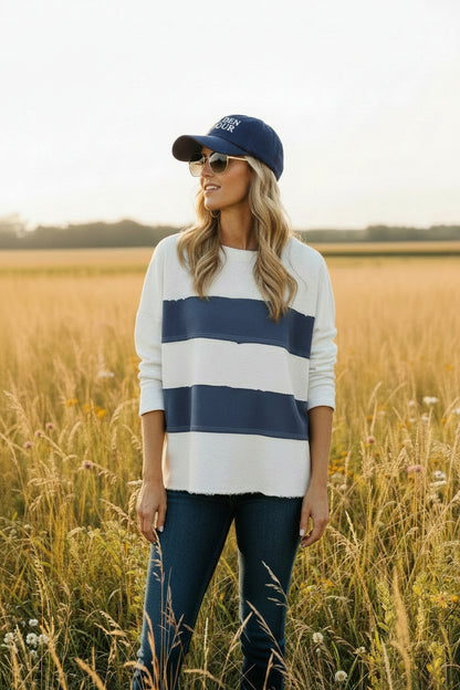 Woman wearing a white and blue striped sweater with blue jeans outdoor.
