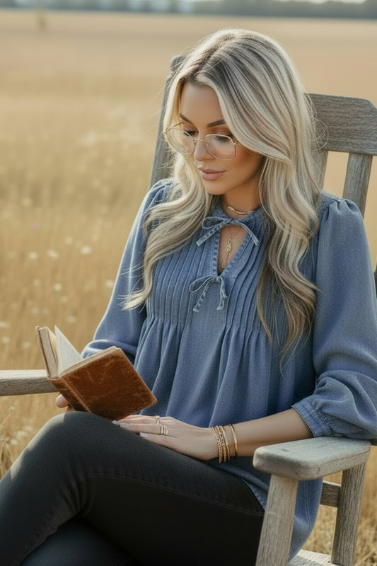 Woman wearing a blue denim blouse with an outdoor blurred background