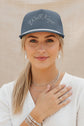 A slate blue snapback cap with 'Well Kept' embroidered in white script across the front, featuring a white stripe along the brim and a matching blue button on top.