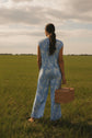 Woman wearing a blue floral jumpsuit standing outdoors with picnic basket