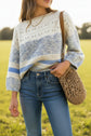 Person wearing a striped sweater and white shorts with a brown bag.